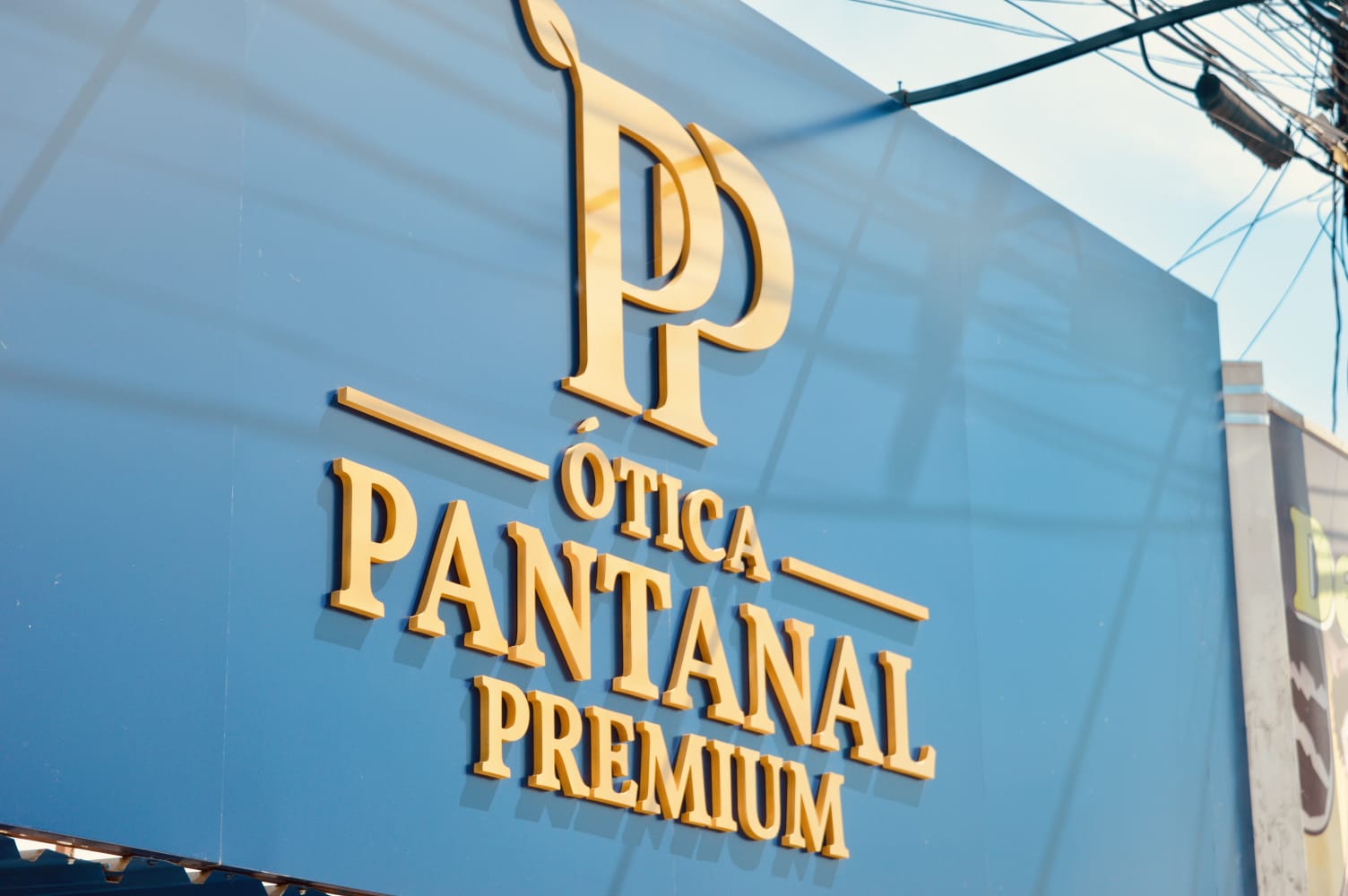 Fachada azul e dourada da Ótica Pantanal Premium em Anastácio